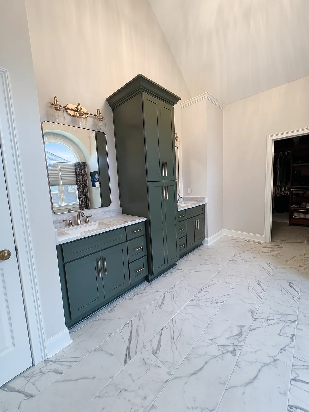 Master bathroom with marble-look porcelain floor tile, a dark green vanity, and a tall linen cabinet