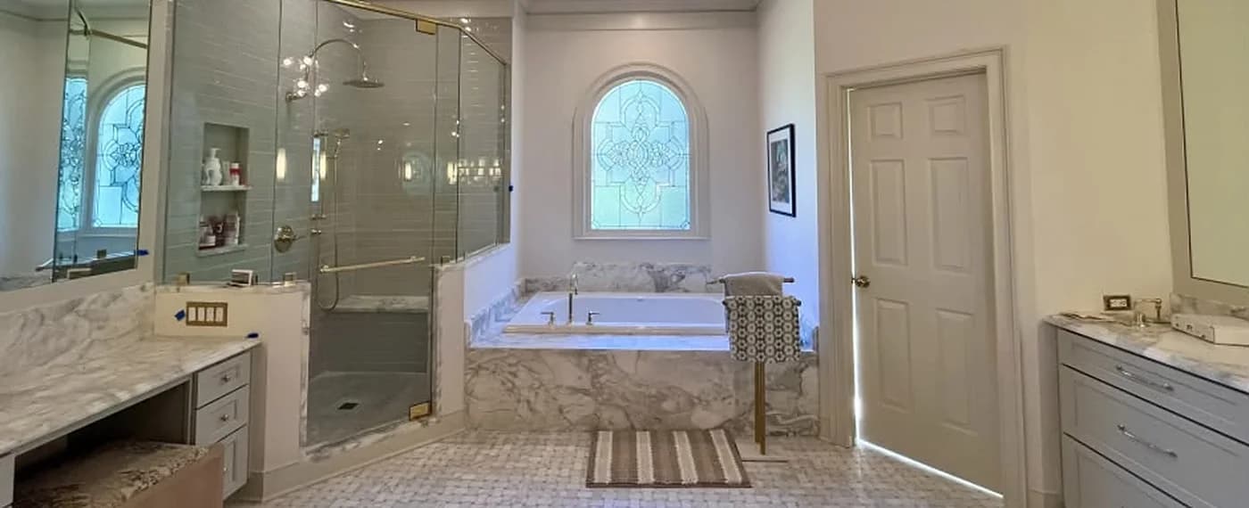 Same master bathroom finished with a glass walk-in shower, marble-look tub deck, and basketweave mosaic floor